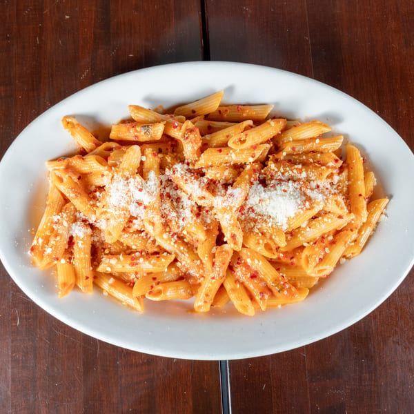 Penne pasta in a creamy red sauce, topped with grated cheese and red pepper flakes.