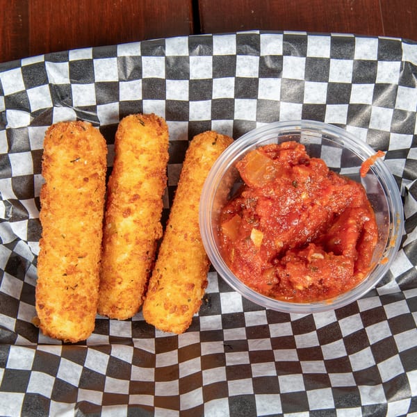 Three golden-brown mozzarella sticks and a clear cup of chunky marinara sauce in a checkered paper-lined basket.